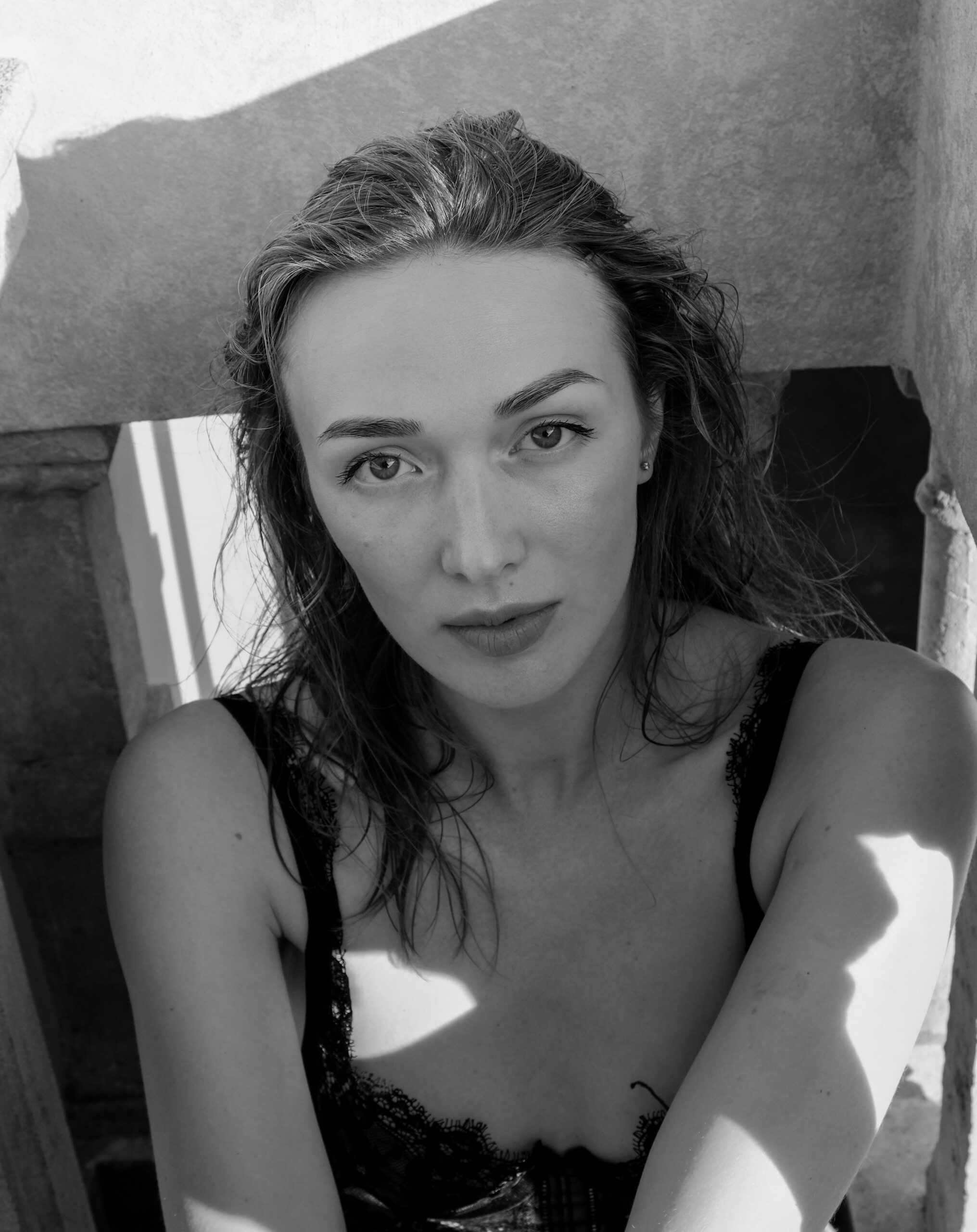 Black-and-white close-up beauty portrait with wet hair and patterned sunlight.