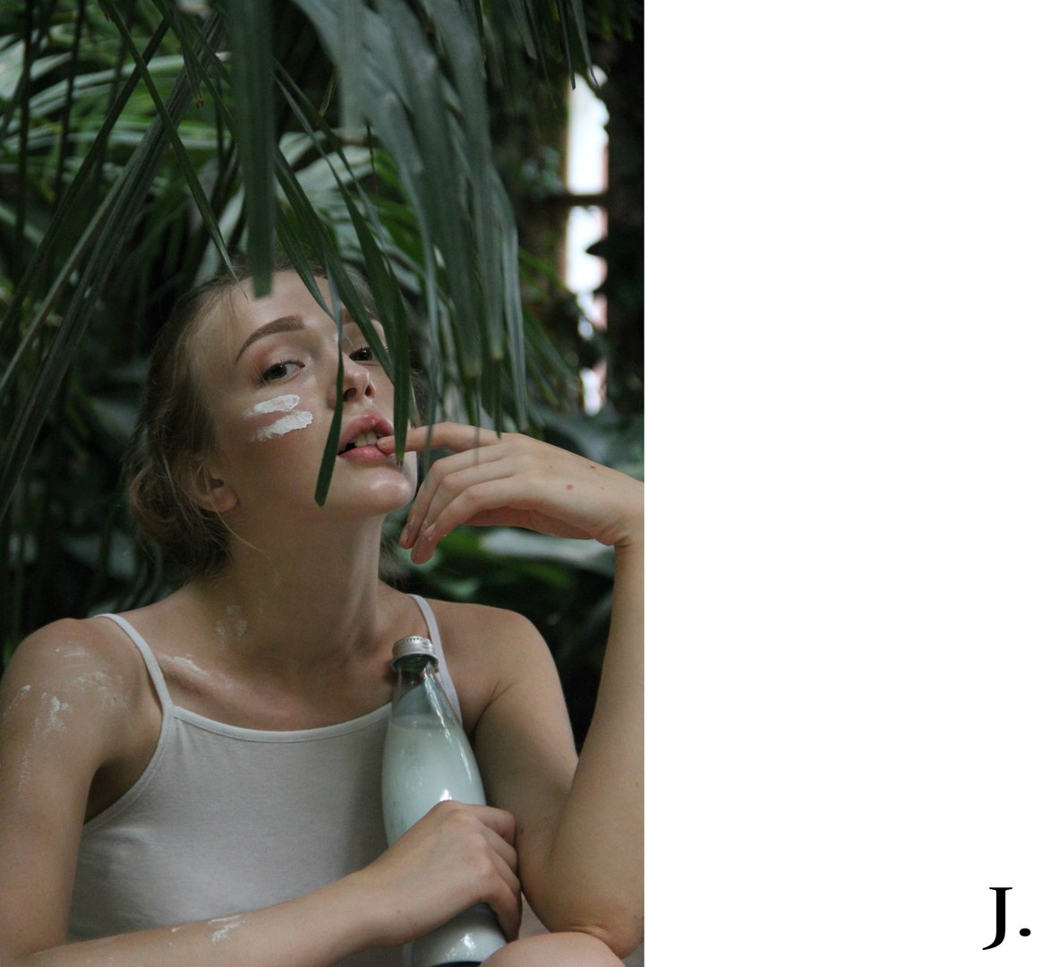 Beauty portrait among tropical leaves with skincare cream applied to the face and shoulder.